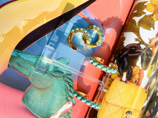 Turquoise beaded earrings on a clear stand with colorful background