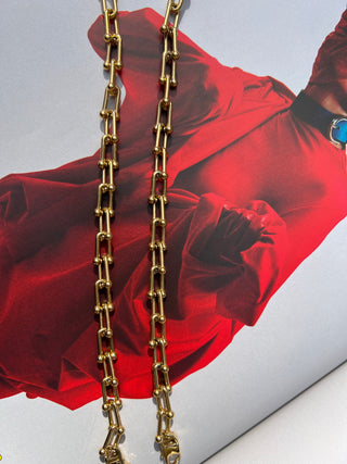 Close-up of gold link bracelet chain on red fabric background. Featured Product: Audrey Bracelet, SKU: BR-21289-001-RG