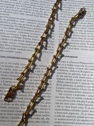 Two gold chain bracelets with rectangular links on a book page background. Featured Product: Audrey Bracelet, SKU: BR-21289-001-RG