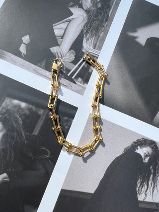 Gold rectangular-link bracelet on black-and-white photo collage. Featured Product: Audrey Bracelet, SKU: BR-21289-001-RG